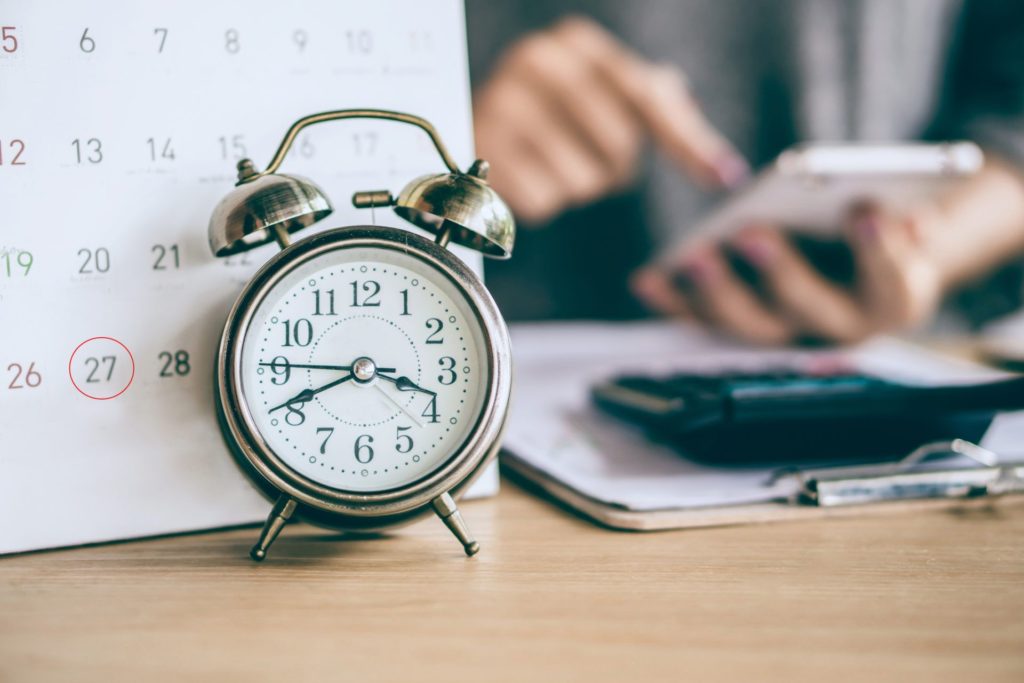 alarm clock in front of calender with circled deadline