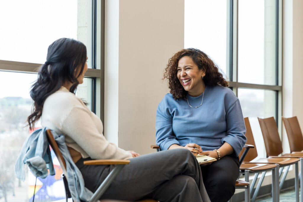 Two women sitting together, one coaching the other